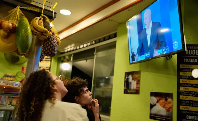 Women watch Brazilian President Luiz Inacio Lula da Silva, who is seeking reelection, speak during a televised presidential debate days before the presidential runoff election in Sao Paulo, Friday, Oct. 23, 2026. (AP Photo/Natacha Pisarenko)