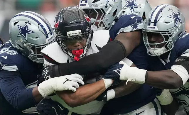 Houston Texans running back David Montgomery is hauled down by Dallas Cowboys defenders during the second half of an NFL football game in Houston, Sunday, Oct. 4, 2026. (AP Photo/Ashley Landis)