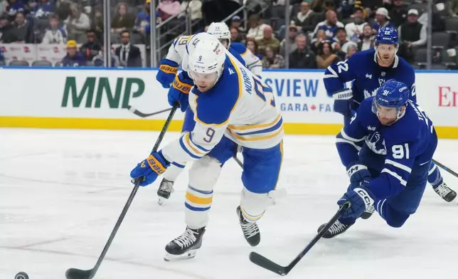 Buffalo Sabres' Josh Norris (9) and Toronto Maple Leafs' John Tavares (91) battle for a rebound during the third period of an NHL hockey game in Toronto, Thursday, Oct. 15, 2026. (Nathan Denette/The Canadian Press via AP)
