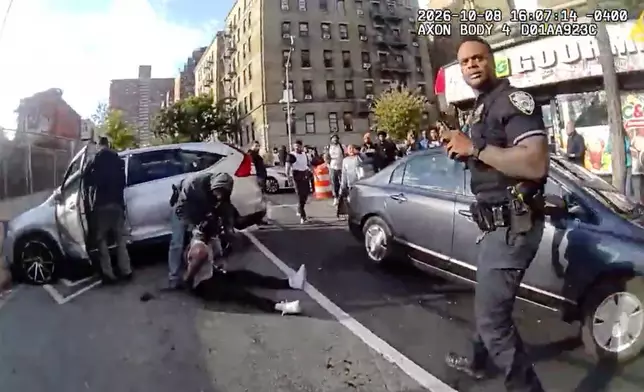 In this image taken from police-worn body camera video released the New York City Police Department (NYPD), law enforcement personnel tend to a Oscar Belgal, 28, a Dominican man who was shot by Federal immigration officers, Thursday, Oct. 8, 2026, in New York, as he drove his car with a 5-year-old boy inside. (NYPD via AP)