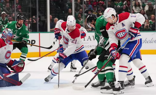 Montréal Canadiens' Kaiden Guhle (21) and Josh Anderson (17) help defend against pressure at the net by Dallas Stars' Wyatt Johnston, second from right, during the first period of an NHL hockey game in Dallas, Thursday Oct. 29, 2026. (AP Photo/Tony Gutierrez)