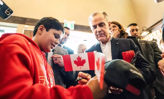 Canada's Prime Minister Mark Carney signs an autograph as he attends a national unity rally in Red Deer, Alberta, Friday Oct. 16, 2026. (John Ulan/The Canadian Press via AP)
