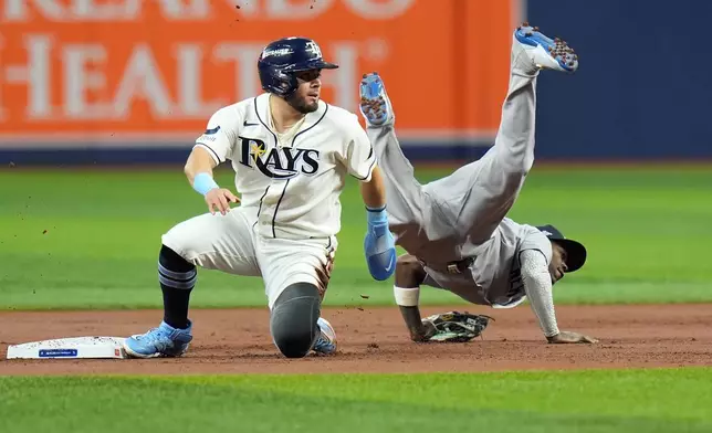 New York Yankees second baseman Jazz Chisholm Jr., right, flips over Tampa Bay Rays' Jonathan Aranda, left, while committing a throwing error allowing Rays' Yandy Díaz to score during the first inning in Game 2 of an American League Division Series baseball game Monday, Oct. 5, 2026, in St. Petersburg, Fla. (AP Photo/Chris O'Meara)