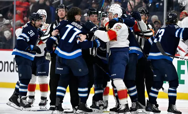 Winnipeg Jets' Tyrel Bauer (77) and Florida Panthers' Brady Tkachuk (8) grab each other during second period NHL action in Winnipeg on Tuesday, Oct. 27, 2026. (Fred Greenslade/The Canadian Press via AP)