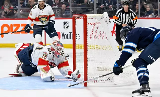 Winnipeg Jets' Adam Lowry (17), right, scores on Florida Panthers' goaltender Akira Schmid (40) during the second period of an NHL hockey game in Winnipeg, Manitoba, Tuesday, Oct. 27, 2026. (Fred Greenslade/The Canadian Press via AP)
