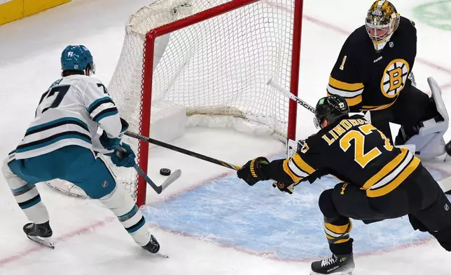 Boston Bruins goalie Jeremy Swayman (1) watches as San Jose Sharks center Michael Misa, left, scores a first-period goal past Bruins defenseman Hampus Lindholm (27) during the first period of an NHL hockey game Saturday, Oct. 24, 2026, in Boston. (AP Photo/Jim Davis)