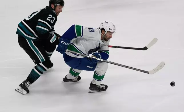 Vancouver Canucks left wing Arshdeep Bains, right, skates toward the puck against San Jose Sharks center Barclay Goodrow (23) during the third period of an NHL hockey game, Thursday, Oct. 29, 2026, in San Jose, Calif. (AP Photo/Jeff Chiu)