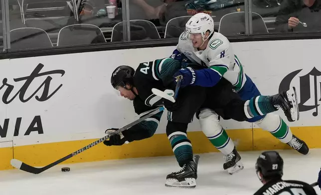 San Jose Sharks left wing Kiefer Sherwood (44) falls toward the puck next to Vancouver Canucks defenseman Zeev Buium during the third period of an NHL hockey game, Thursday, Oct. 29, 2026, in San Jose, Calif. (AP Photo/Jeff Chiu)