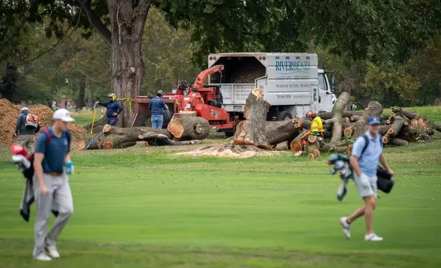 Golfers pass workers as the National Park Service begins cutting down trees at East Potomac Golf Links, Saturday, October 10, 2026, in Washington. (AP Photo/Nathan Howard)