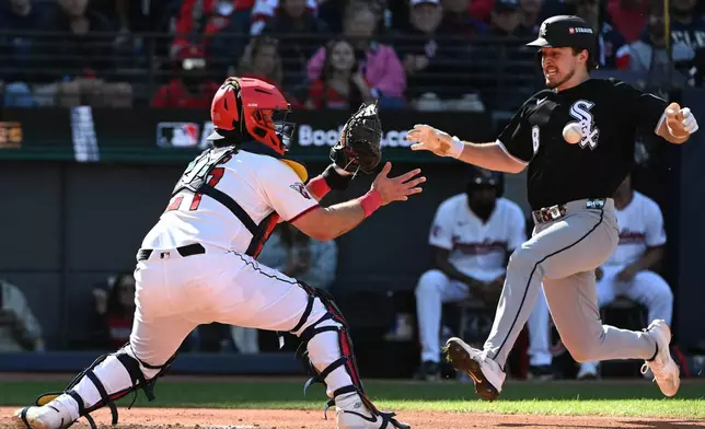 Cleveland Guardians catcher Austin Hedges looks to receive the throw to the plate as Chicago White Sox's Kyle Teel (8) runs home to score on an RBI double from Colson Montgomery during the seventh inning in Game 1 of baseball's American League Division Series, Saturday, Oct. 3, 2026, in Cleveland. (AP Photo/Phil Long)