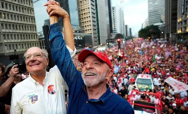 Brazilian President Luiz Inacio Lula da Silva, right, who is running for reelection, and his running mate Geraldo Alckmin raise their arms in unison at the end of their final campaign rally, a day ahead of the presidential runoff election in Sao Paulo, Brazil, Saturday, Oct. 24, 2026. (AP Photo/Natacha Pisarenko)