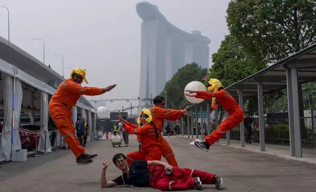 Workers pose for photos during a hazy day ahead of the Singapore Formula One Grand Prix weekend at the Marina Bay Street Circuit in Singapore, Friday, Oct. 9, 2026. (AP Photo/Ng Han Guan)