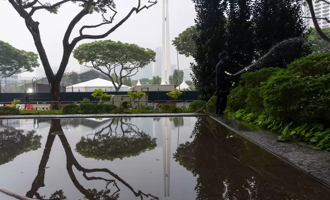 A gardener waters plants during a hazy day ahead of the Singapore Formula One Grand Prix weekend at the Marina Bay Street Circuit in Singapore, Friday, Oct. 9, 2026. (AP Photo/Ng Han Guan)