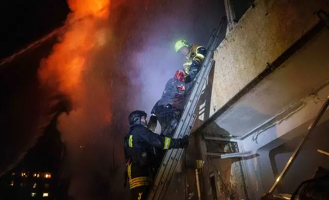 Rescue workers help Leonid, an injured resident, down a ladder from his balcony in a multi-story residential building damaged in a Russian missile strike in Kyiv, Ukraine, Tuesday, Oct. 13, 2026. (AP Photo/Evgeniy Maloletka)