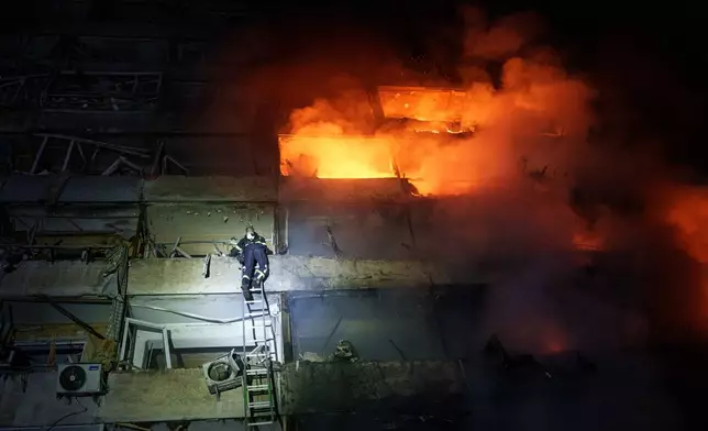 A rescue worker climbs a ladder to a multi-story residential building damaged in a Russian missile strike in Kyiv, Ukraine, Tuesday, Oct. 13, 2026. (AP Photo/Evgeniy Maloletka)