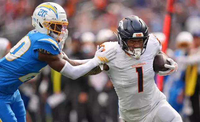 Denver Broncos tight end Evan Engram, runs the ball as Los Angeles Chargers cornerback Cam Hart defends during the first half of an NFL football game, Sunday, Oct. 11, 2026, in Inglewood, Calif. (AP Photo/Scott Strazzante)