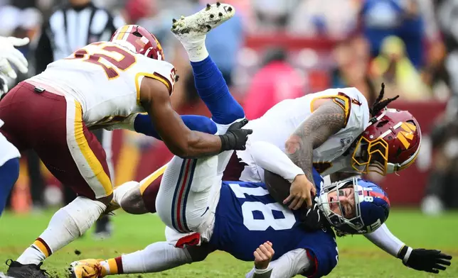 New York Giants quarterback J.J. McCarthy (18) is tackled by Washington Commanders' Frankie Luvu (4) during the second half of an NFL football game in Landover, Md., Sunday, Oct. 11, 2026. (AP Photo/Nick Wass)
