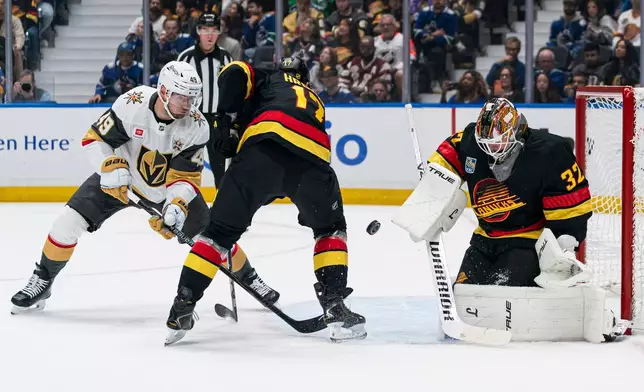 Las Vegas Golden Knights' Ivan Barbashev's (49) redirect is stopped by Vancouver Canucks goalie Kevin Lankinen (32) as Canucks' Filip Hronek (17) tries to help defend on the play during the first period of an NHL hockey game in Vancouver, British Columbia, Sunday, Oct. 4, 2026. (Rich Lam/The Canadian Press via AP)