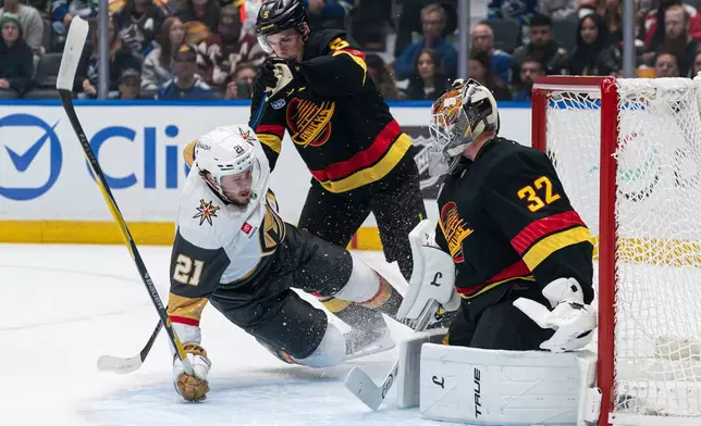 Vancouver Canucks' Tom Willander (5) knocks down Las Vegas Golden Knights' Brett Howden (21) as he crashes the net of goalie Kevin Lankinen (32) during the first period of an NHL hockey game in Vancouver, Sunday, Oct. 4, 2026. (Rich Lam/The Canadian Press via AP)