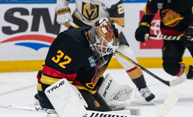 Vancouver Canucks' goalie Kevin Lankinen (32) makes a pad save as Las Vegas Golden Knights' Brett Howden (21) looks for a rebound during an NHL hockey game in Vancouver, Sunday, Oct. 4, 2026. (Rich Lam/The Canadian Press via AP)
