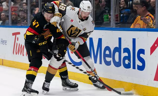 Las Vegas Golden Knights' Tomas Hertl (48) tries to fight of the check of Vancouver Canucks' Paul Cotter (47) during the first period of an NHL hockey game in Vancouver, Sunday, Oct. 4, 2026. (Rich Lam/The Canadian Press via AP)