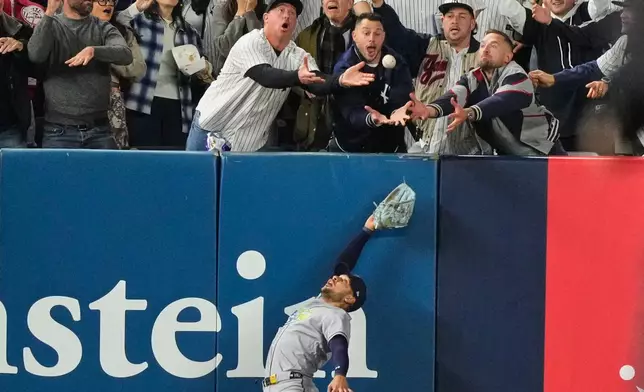 Tampa Bay Rays left fielder Victor Mesa Jr. makes an attempt on a ball interfered with by fans that umpires reviewed and ruled a run-scoring double by New York Yankees' Anthony Volpe during the sixth inning in Game 3 of baseball's American League Division Series, Wednesday, Oct. 7, 2026, in New York. (AP Photo/Yuki Iwamura)