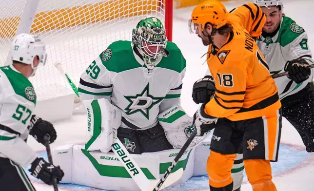 Dallas Stars goaltender Jake Oettinger (29) blocks a shot by Pittsburgh Penguins' Tommy Novak (18) with Stars' Lian Bichsel, right, defending during the first period of an NHL hockey game in Pittsburgh, Saturday, Oct. 10, 2026. (AP Photo/Gene J. Puskar)