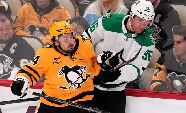 Pittsburgh Penguins' Nick Robertson (14) checks Dallas Stars' Mikko Rantanen (96) into the boards during the first period of an NHL hockey game in Pittsburgh, Saturday, Oct. 10, 2026. (AP Photo/Gene J. Puskar)