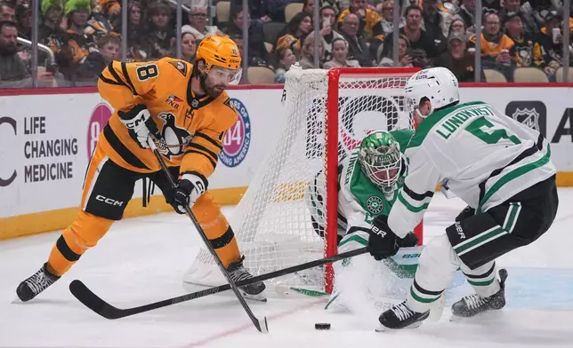 Pittsburgh Penguins' Tommy Novak (18) cannot shoot with Dallas Stars' Nils Lundkvist (5) defending in front of Stars goalie Jake Oettinger, center, during the second period of an NHL hockey game in Pittsburgh, Saturday, Oct. 10, 2026. (AP Photo/Gene J. Puskar)