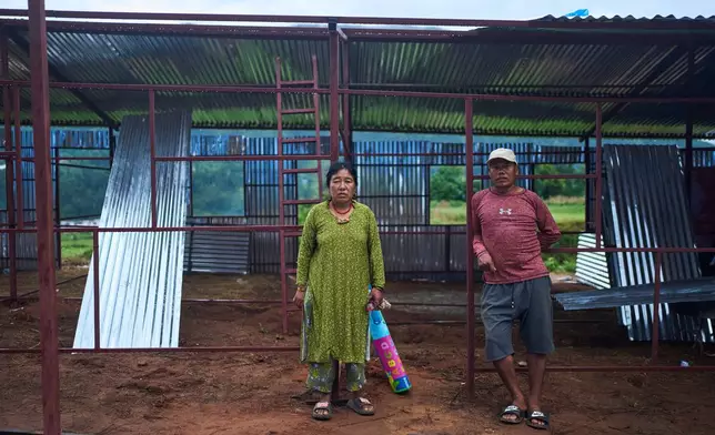Zyazong Tamang, right, and his wife, Nyangsal Tamang, who survived the Nepal's 2015 earthquake and the flash floods in August this year, pose for a photograph at a temporary holding center in Nepal's Nuwakot district, Sept. 23, 2026. (AP Photo/Niranjan Shrestha)