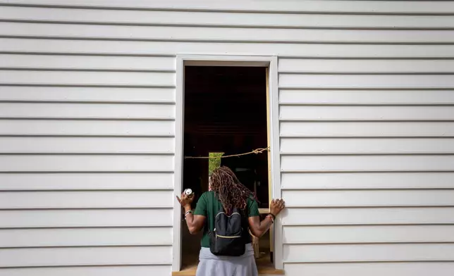 Tavianna Gwaltney looks into the reconstructed African Baptist Meeting House, now known as First Baptist Church of Williamsburg, during a community-wide rededication ceremony in Williamsburg, Va., Friday, Oct. 9, 2026. (AP Photo/Mike Kropf)
