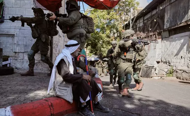 Israeli soldiers take positions during a military operation at a market in Nablus, West Bank, Sunday, Sept. 27, 2026. (AP Photo/Majdi Muhammad)