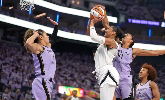 Las Vegas Aces center A'ja Wilson, third from right, is fouled by Golden State Valkyries center Kiah Stokes (41) as Valkyries' Veronica Burton, left, defends during the first half of Game 1 of the WNBA basketball semifinals in San Francisco, Sunday, Oct. 4, 2026. (AP Photo/Tony Avelar)