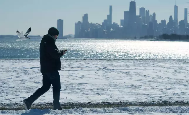 FILE - A person walks near the snow-covered sand at Lake Michigan in Chicago, Jan. 28, 2026. (AP Photo/Nam Y. Huh, File)