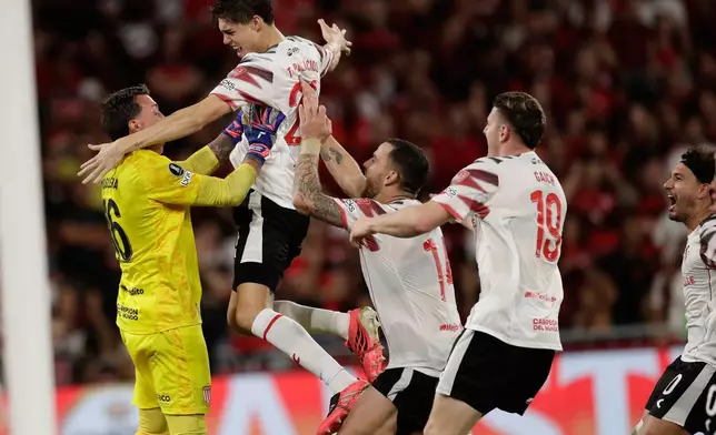Players of Argentina's Estudiantes de La Plata celebrate with goalkeeper Nestor Muslera after winning a penalty shootout against Brazil's Flamengo during the second leg of a Copa Libertadores semifinal soccer match in Rio de Janeiro, Thursday, Oct. 22, 2026. (AP Photo/Bruna Prado)