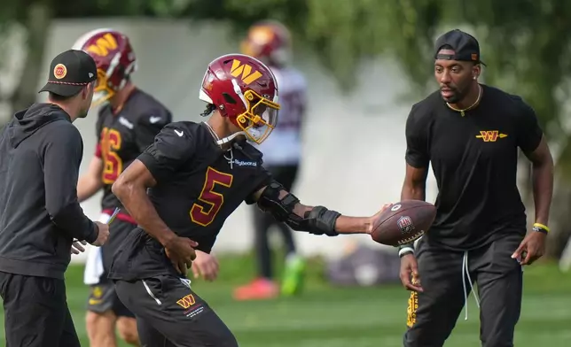 Washington Commanders' quarterback Jayden Daniels passes the ball during an NFL football practice in Hertfordshire, England, Friday, Oct. 2, 2026. (AP Photo/Alastair Grant)