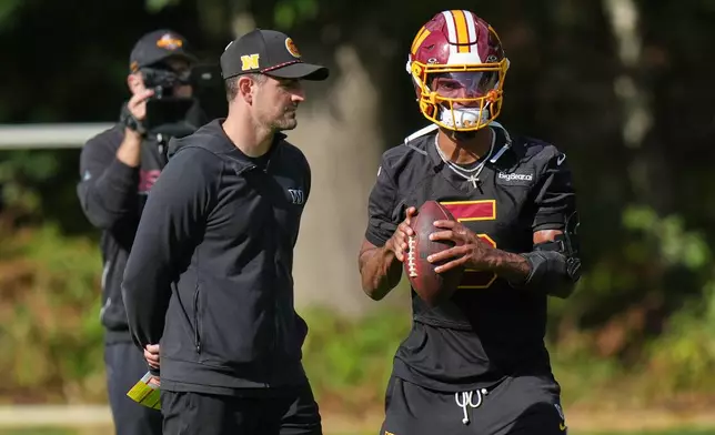 Washington Commanders' quarterback Jayden Daniels holds the ball during an NFL football practice in Hertfordshire, England, Friday, Oct. 2, 2026. (AP Photo/Alastair Grant)
