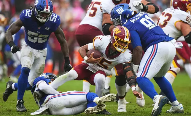 New York Giants' Dru Phillips (22) tackles Washington Commanders quarterback Jayden Daniels (5) as he runs past Darius Alexander (91) and Arvell Reese (52) during the second half of an NFL football game in Landover, Md., Sunday, Oct. 11, 2026. (AP Photo/Stephanie Scarbrough)