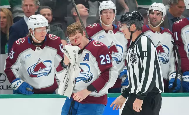 Colorado Avalanche center Nathan MacKinnon (29) skates with linesman Ben O'Quinn (91) after fighting with Dallas Stars center Roope Hintz, not visible, during the second period of an NHL hockey game Tuesday, Oct. 13, 2026, in Dallas. (AP Photo/Julio Cortez)