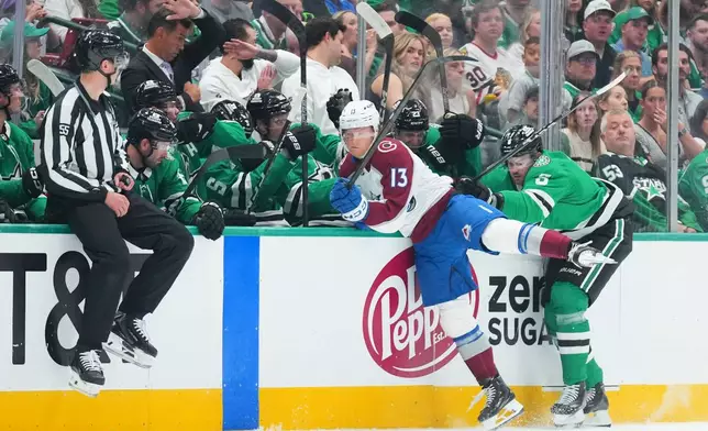 Colorado Avalanche right wing T.J. Hughes (13) hits the boards while competing for the puck against Dallas Stars defenseman Lian Bichsel (6) during the first period of an NHL hockey game Tuesday, Oct. 13, 2026, in Dallas. (AP Photo/Julio Cortez)