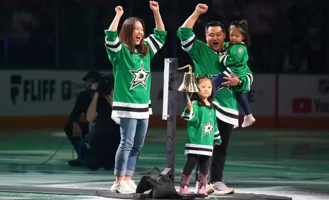 Kaylin Lee, bottom, rings the bell as her parents react during a pregame moment celebrating Lee being cancer free prior to an NHL hockey game between the Dallas Stars and the Colorado Avalanche, Tuesday, Oct. 13, 2026, in Dallas. (AP Photo/Julio Cortez)