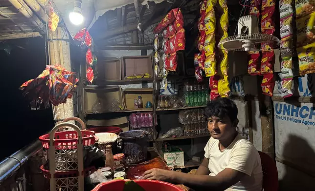 In this photo taken with a phone, Mohammed Hares keeps his small shop open at night using a light powered by solar panels on Oct. 2, 2026, in Teknaf, Bangaldesh. (AP Photo/Abdul Khan Dkl)