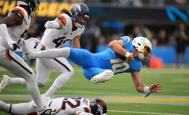 Los Angeles Chargers quarterback Justin Herbert, right, is taken down by Denver Broncos linebacker Que Robinson, left, linebacker Alex Singleton, second from left, and safety Brandon Jones during the second half of an NFL football game, Sunday, Oct. 11, 2026, in Inglewood, Calif. (AP Photo/Gregory Bull)