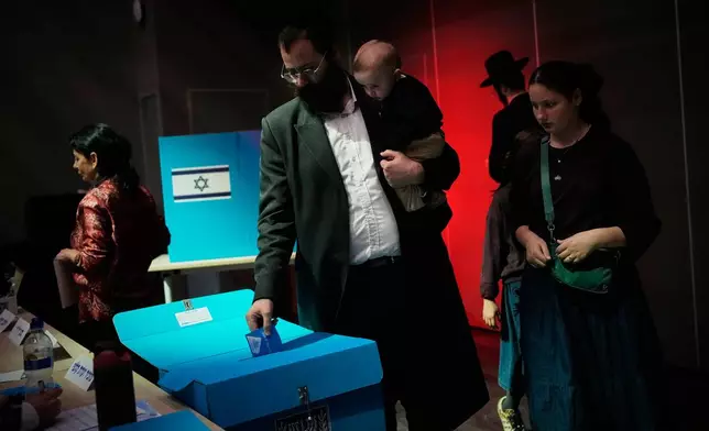 An ultra-Orthodox Jewish man holds his child as he casts his ballot at a school serving as a polling station during Israel's general election in Jerusalem, Tuesday, Oct. 27, 2026. (AP Photo/Ohad Zwigenberg)