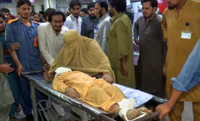 A woman mourns next to the body of a boy, who was killed in the roof collapse of a private school, at a hospital in Peshawar, Pakistan, Thursday, Oct. 15, 2026. (AP Photo/Muhammad Zubair)