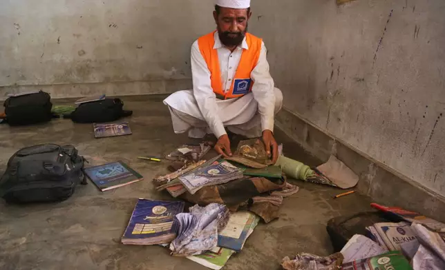 A rescue worker collects books and school bags of victim children at the the site of a roof collapse of a private school, in Peshawar, Pakistan, Pakistan, Thursday, Oct. 15, 2026. (AP Photo/Muhammad Zubair)