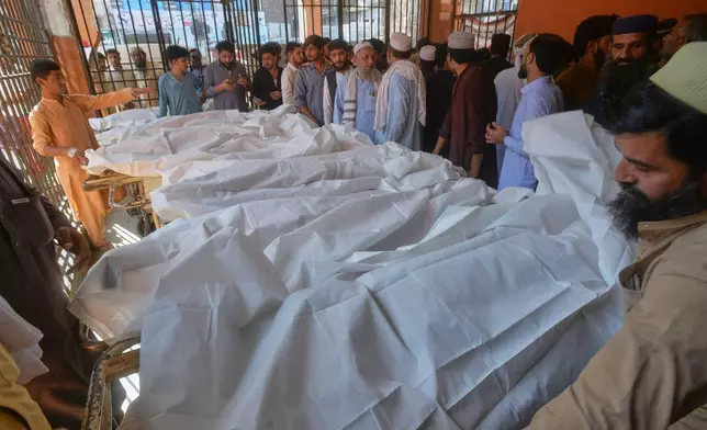 Parents gather at a hospital next to the bodies of children, who died in the roof collapse of a private school, in Peshawar, Pakistan, Thursday, Oct. 15, 2026. (AP Photo/Muhammad Zubair)