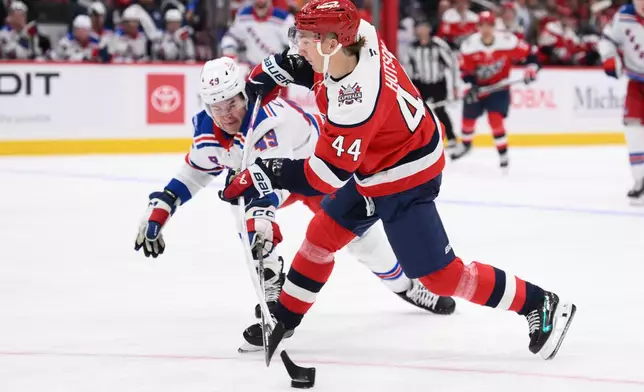 Washington Capitals defenseman Cole Hutson (44) shoots against New York Rangers right wing Jaroslav Chmelar (49) during the first period of an NHL hockey game, Friday, Oct. 9, 2026, in Washington. (AP Photo/Nick Wass)