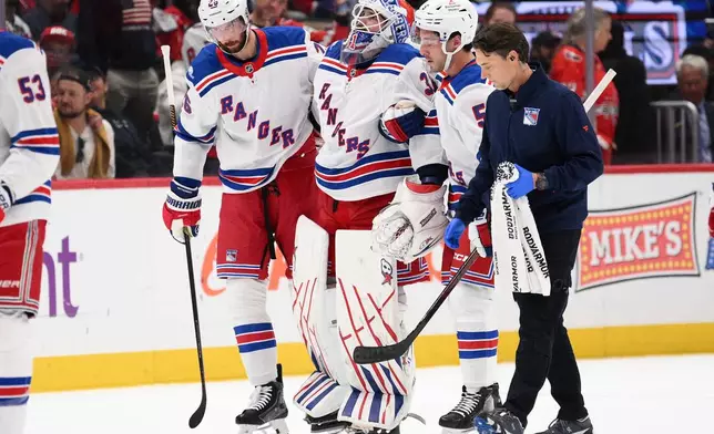 New York Rangers goaltender Igor Shesterkin, third from right, is helped to the bench after he was injured during the second period of an NHL hockey game against the Washington Capitals, Friday, Oct. 9, 2026, in Washington. (AP Photo/Nick Wass)