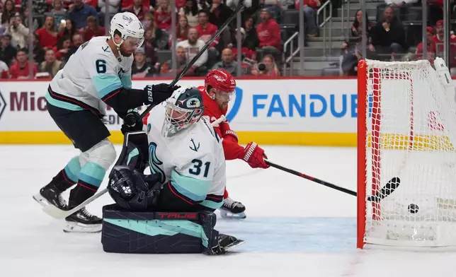 Detroit Red Wings left wing Viktor Arvidsson (33) scores on Seattle Kraken goaltender Philipp Grubauer (31) as Adam Larsson (6) defends in the first period of an NHL hockey game Friday, Oct. 9, 2026, in Detroit. (AP Photo/Paul Sancya)